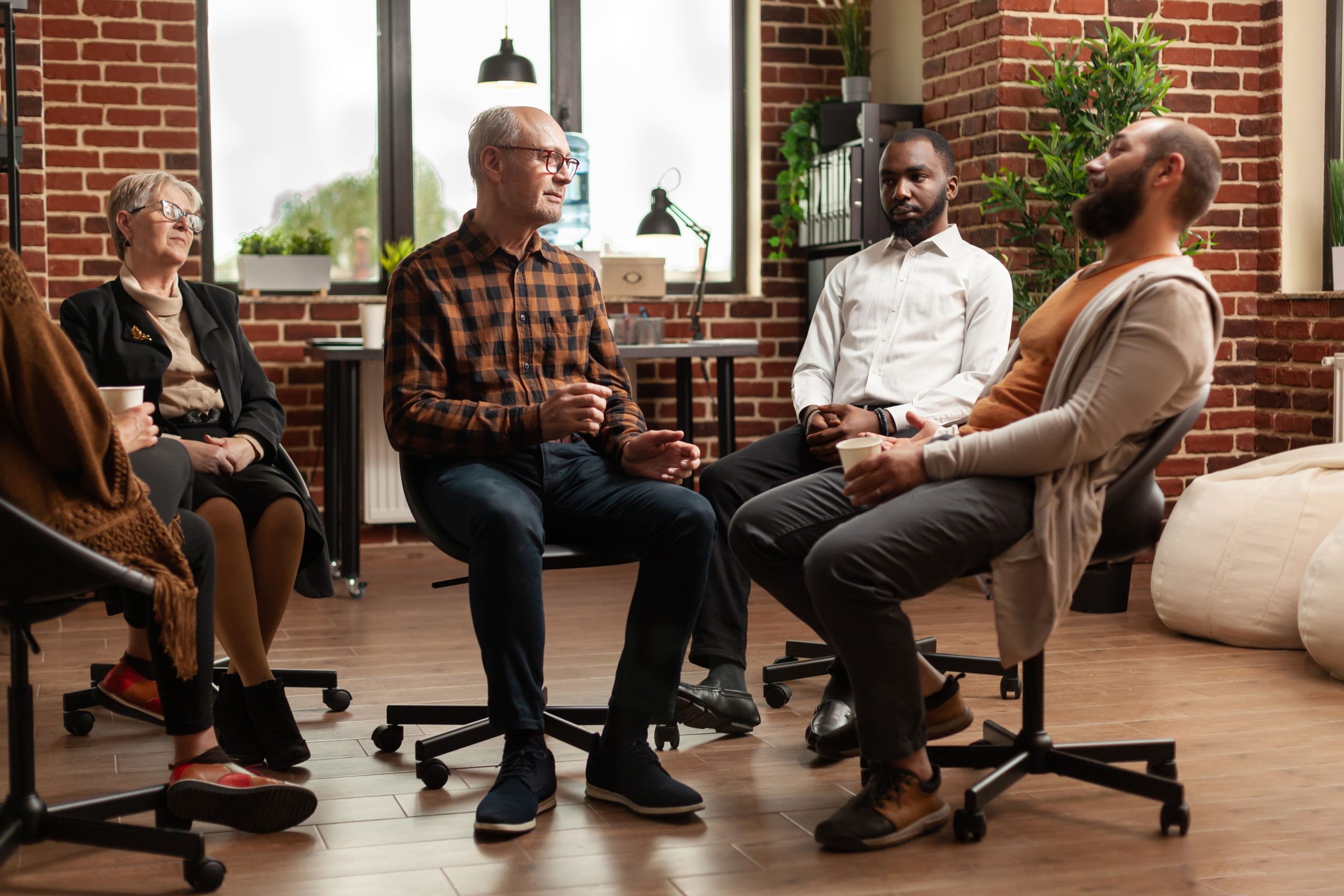 Group therapy session in Louisville KY with adults seated in a circle, engaged in open discussion.